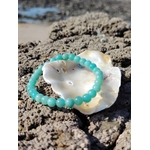 Bracelet en amazonite posé dans un coquillage sur rochers en Bretagne face à la mer, douceur émotionnelle, harmonie et sérénité