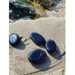 Galets en quartz fumé posés sur la roche en Bretagne près de l’eau et du sable, pierres naturelles associées à l’équilibre émotionnel, au calme et à l’ancrage doux.