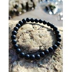 Bracelet shungite 6 mm noir profond sur pierre texturée, photo Bretagne, ancrage solide, protection discrète et esprit plus stable