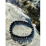 Bracelet shungite 6 mm sur galet clair au soleil, ambiance minérale en Bretagne, stabilité du ressenti et protection face aux tensions extérieures