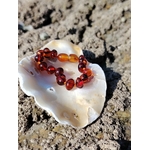 Bracelet bébé ambre sur coquillage parmi les rochers en Bretagne, perles naturelles couleur cognac, idée cadeau naissance pleine de douceur