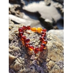Bracelet bébé en ambre naturel sur rochers en Bretagne près de l’eau, perles miel cognac et fermoir de sécurité, bijou doux et lumineux