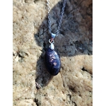 Pendentif en iolite ou cordiérite sur chaîne argentée, suspendu entre les rochers en Bretagne, bijou en pierre naturelle associé à la vision intérieure, au calme et à la présence à soi.