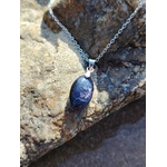 Pendentif en iolite ou cordiérite sur chaîne argentée, photographié sur rochers en Bretagne près de l’eau, bijou en pierre naturelle associé au discernement, à la sérénité et à la profondeur intérieure.