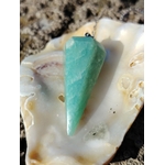 Pendule en amazonite bleu-vert dans un coquillage posé sur roche en Bretagne, photo douce évoquant apaisement, intuition et équilibre.