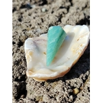 Pendule en amazonite bleu-vert dans un coquillage sur roche en Bretagne, image apaisante inspirant douceur, intuition et harmonie.