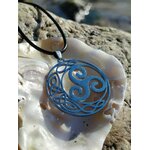 Pendentif Triskell bleu sur coquillage en décor breton minéral, suspendu à un cordon noir, symbole d’unité et d’énergie cyclique
