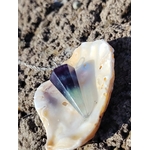 Pendule en fluorite posé dans un coquillage sur un décor minéral, outil de divination à l’ambiance douce et mystique évoquant intuition, clarté mentale et recentrage.