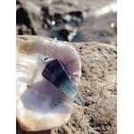 Pendule en fluorite présenté comme outil de divination sur un décor minéral, dans une ambiance douce et mystique évoquant clarté mentale, intuition et recentrage.