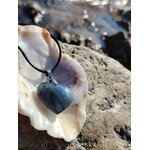 Pendentif cœur en labradorite sur cordon noir, présenté dans un coquillage sur rochers en Bretagne, collier pierre naturelle associé au réconfort, à l’intuition et à la paix intérieure.