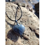 Pendentif cœur en labradorite sur cordon noir, posé sur les rochers en Bretagne, dans une ambiance minérale et lumineuse évoquant protection, intuition et apaisement