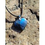 Pendentif cœur en labradorite sur cordon noir, posé sur rochers en Bretagne, bijou en pierre naturelle associé à l’intuition, à la stabilité intérieure et à la protection douce.