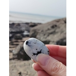Galet de péristérite tenu en main face à la mer en Bretagne, pierre de lune arc-en-ciel évoquant la délicatesse, l’écoute de soi et la tranquillité intérieure.