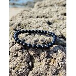 Bracelet obsidienne dorée 6 mm sur rochers marins en Bretagne, perles sombres brillantes, discernement et stabilité intérieure