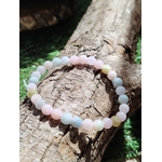 Bracelet Morganite 6 mm posé sur tronc, perles pastel lumineuses en décor naturel, bijou en pierre naturelle associé à la tendresse, au calme émotionnel et à la douceur intérieure.