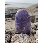 Lépidolite forme libre aux nuances violettes posée sur rocher en Bretagne face à la mer, pierre naturelle évoquant le lâcher-prise, la paix du mental et l’harmonie intérieure.