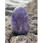 Lépidolite forme libre violette posée sur roche bretonne au bord de la mer, pierre naturelle aux nuances lilas associée au réconfort, au relâchement et à la paix intérieure.