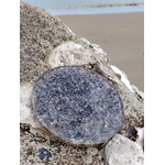 Plateau de rechargement orgonite obsidienne noire posé sur roche marine en Bretagne avec plage en arrière-plan, face minérale gris noir, énergie protectrice et retour au calme.