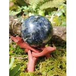 Sphère iolite ou cordiérite sur rondin de bois en forêt en Bretagne avec pomme de pin, pierre bleu gris polie, clarté intérieure et inspiration.