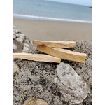 Trois bâtons de Palo Santo photographiés sur roche côtière en Bretagne avec plage en arrière-plan, bois naturel du Pérou, purification douce et harmonie intérieure.