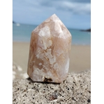Pointe agate fleur de cerisier sur roche marine texturée avec mer en arrière-plan, pierre rose sable aux motifs naturels, paix intérieure et harmonie.