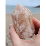 Pointe agate fleur de cerisier tenue en main au bord de mer en Bretagne, nuances beige rosé et dessins floraux, calme du cœur et confiance en soi.