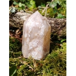 Pointe agate fleur de cerisier sur tapis de mousse devant une branche boisée, pierre aux inclusions fleuries, sérénité émotionnelle et croissance intérieure.