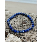 Bracelet Lapis Lazuli 6 mm posé sur roche marine couverte de petits coquillages, perles bleu outremer naturelles, confiance intérieure et expression sincère.