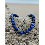 Bracelet Lapis Lazuli 6 mm formant un cœur sur roche de bord de mer, perles bleu intense aux touches dorées, vérité intérieure et harmonie émotionnelle.