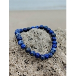 Bracelet Lapis Lazuli 6 mm photographié sur rocher coquillé en lumière naturelle, perles bleu profond marbrées, assurance personnelle et apaisement du mental.