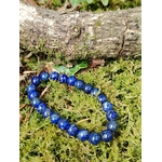 Bracelet Lapis Lazuli 6 mm allongé sur tapis de mousse sous une branche boisée, perles bleu nuit naturelles, sagesse intérieure et recentrage.