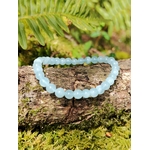 Bracelet Aigue-Marine 6 mm sur branche couverte de mousse, perles bleu clair naturelles, apaisement émotionnel et expression plus fluide.