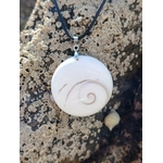 Pendentif rond œil de Sainte Lucie sur cordon noir, photographié sur rocher marin texturé, bijou coquillage naturel porte-bonheur, équilibre émotionnel et sérénité.