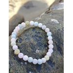 Bracelet Morganite 6 mm photographié sur roche bretonne au bord de l’eau, perles roses, bleues et vert pâle, bijou en pierre naturelle évoquant la sérénité, la délicatesse et l’équilibre affectif.