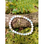Bracelet Morganite 6 mm posé sur branche moussue en forêt en Bretagne, perles pastel aux teintes tendres, bijou en pierre naturelle relié au réconfort émotionnel, à la sensibilité apaisée et à l’écoute de soi.