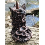Brûleur d’encens à refoulement arbre en résine bronze posé sur bois en forêt avec ruisseau en arrière-plan, visage sculpté, coupelles en cascade et cône d’encens sur le dessus.