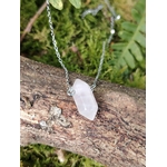 Pendentif pointe en quartz rose sur chaîne argentée, pierre rose pâle posée sur une branche avec mousse verte, symbole de douceur, apaisement émotionnel et ouverture du cœur.