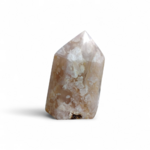 Pointe agate fleur de cerisier sur fond blanc, pierre rose beige polie aux motifs floraux, douceur émotionnelle et harmonie intérieure.