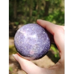 Sphère lépidolite tenue en main en forêt en Bretagne, pierre violette polie aux reflets doux, calme intérieur et équilibre émotionnel.