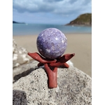 Sphère lépidolite sur roche marine en Bretagne face à la plage avec support en bois, pierre lavande naturelle, détente émotionnelle et énergie apaisante.