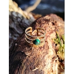 Bague ajustable dorée avec pierre verte sur souche en forêt, acier inoxydable brillant et pierre verte marbrée, stabilité émotionnelle et charme naturel.