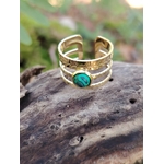 Bague pierre verte ajustable dorée sur bois naturel en extérieur, monture triple anneau et cabochon vert effet malachite, raffinement lumineux et sérénité.