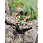 Bague dorée ajustable en acier inoxydable posée dans un tronc creux en forêt, pierre verte ovale au visuel malachite, douceur intérieure et équilibre émotionnel.