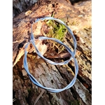 Créoles argentées torsadées en gros plan sur bois naturel avec mousse, boucles d’oreilles en acier inoxydable à la finition lisse et lumineuse.