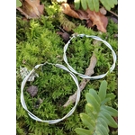Boucles d’oreilles créoles argentées effet torsadé sur mousse en forêt, acier inoxydable éclatant, bijou léger et élégant pour tous les jours.