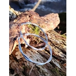 Créoles argentées effet torsadé lisse sur bois naturel au bord de mer en Bretagne, boucles d’oreilles en acier inoxydable au rendu moderne et épuré.
