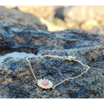 Bracelet soleil doré en acier inoxydable avec rhodonite rose posé sur roche en bord de mer en Bretagne, motif solaire délicat, harmonie intérieure et style raffiné.