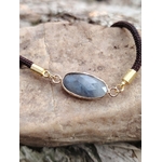 Bracelet médaillon ovale facetté en labradorite en gros plan sur pierre naturelle, monture dorée et nuances gris ardoise, sérénité et élégance sobre.