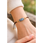 Bracelet médaillon ovale en labradorite facettée porté au poignet, cordon brun et reflets bleu gris de la pierre, clarté intérieure et style raffiné.