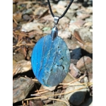 Pendentif ovale en labradorite aux reflets bleus tenu en main face à la mer en Bretagne, pierre naturelle polie et bélière argentée, apaisement du mental et intuition.
